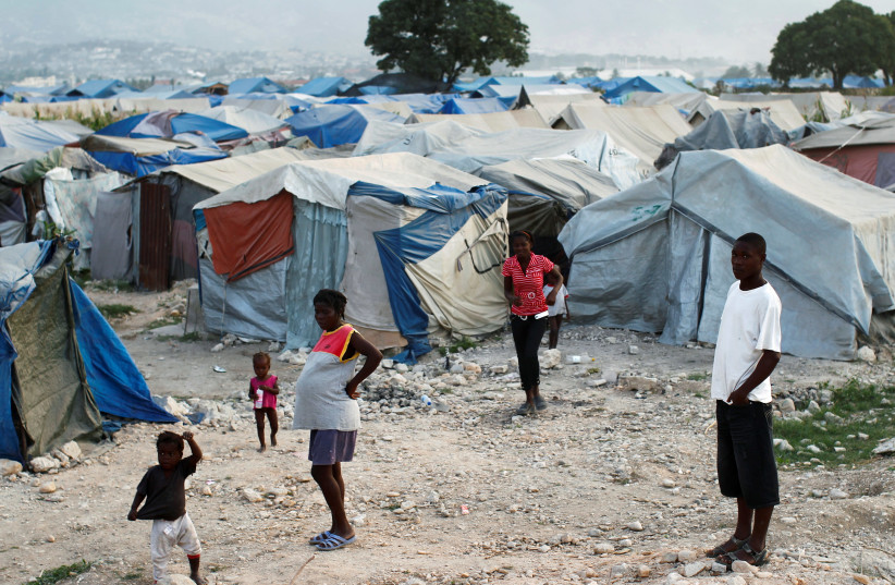 Haitians made homeless in the 2010 earthquake stand outside their tents on the outskirts of Port-au-Prince January 13, 2011 (credit: REUTERS)
