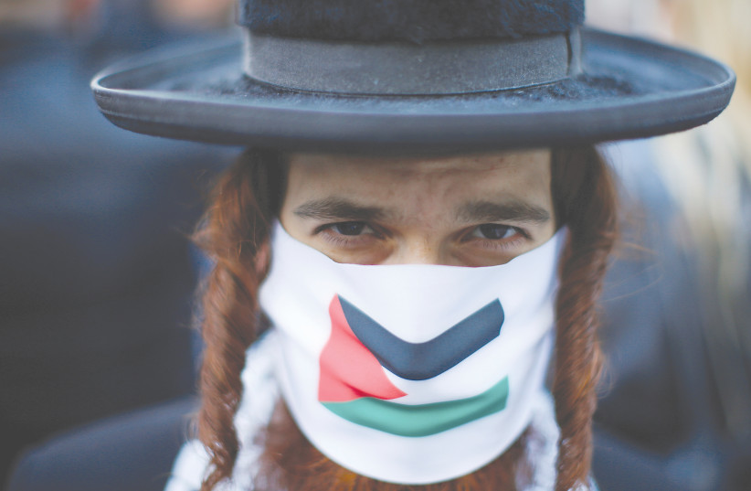  AN ANTI-ISRAELI Jewish Orthodox activist wears a face mask with the Palestinian flag during a protest near the Israeli Consulate following a flare-up of Israeli-Palestinian violence in the Manhattan borough of New York City in May. (photo credit: EDUARDO MUNOZ / REUTERS)