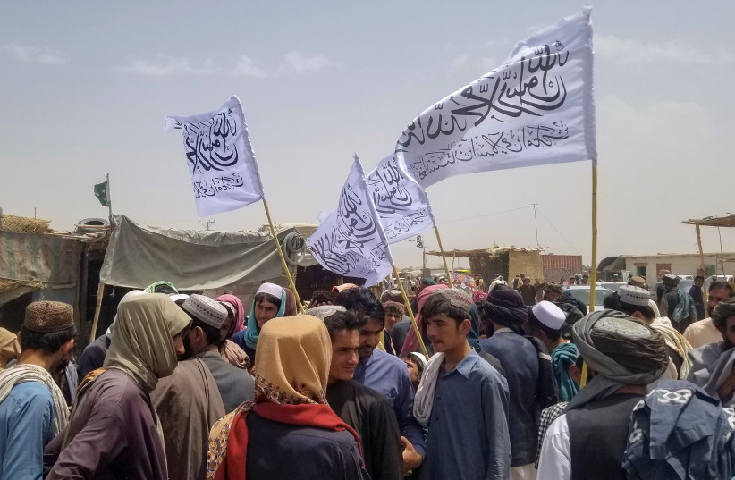  People with Taliban's flags gather to welcome a man (not pictured) who was released from prison in Afghanistan, upon his arrival at the Friendship Gate crossing point at the Pakistan-Afghanistan border town of Chaman, Pakistan August 16, 2021. (photo credit: REUTERS)