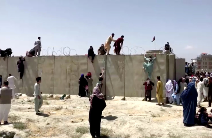  People climb a barbed wire wall to enter the airport in Kabul, Afghanistan August 16, 2021, in this still image taken from a video. (credit: REUTERS TV/via REUTERS)
