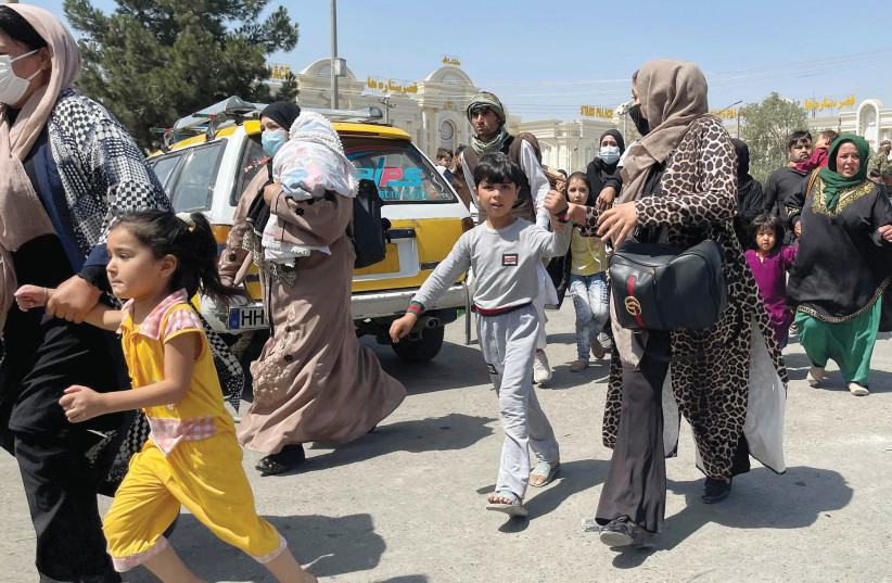  WOMEN WITH their children try to get inside Hamid Karzai International Airport in Kabul on Monday. (photo credit: REUTERS)