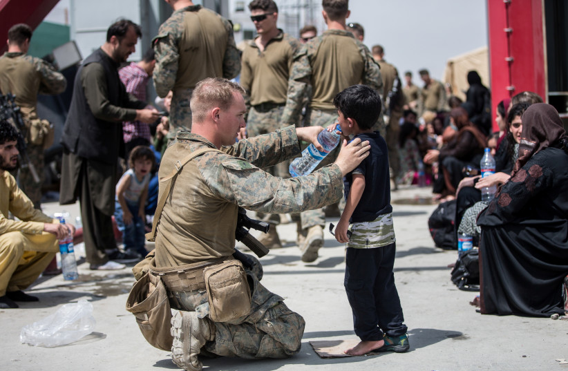  A U.S. Marine with the 24th Marine Expeditionary Unit (MEU) provides water to a child during an evacuation at Hamid Karzai International Airport, Kabul, Afghanistan, in this photo taken on August 20, 2021 (credit: SGT SAMUEL RUIZ/US MARINE CORPS/HANDOUT VIA REUTERS)