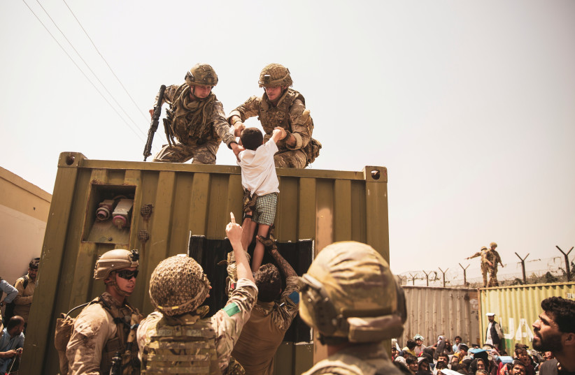  UK coalition forces, Turkish coalition forces, and US Marines assist a child during an evacuation at Hamid Karzai International Airport, Kabul (credit: SGT. VICTOR MANCILLA/US MARINE CORPS/HANDOUT VIA REUTERS)
