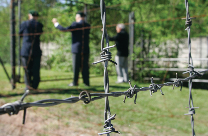 Jewish American World War II veterans stand next to the barbed wire fence of the Dachau concentration camp at the 62th memorial of its liberation in May 2007.