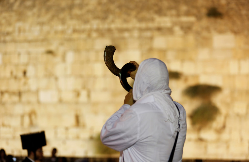  A Jewish worshipper blows a Shofar as he takes part in Slichot at the Western Wall in Jerusalem's Old City, 2017 (photo credit: RONEN ZVULUN/REUTERS)