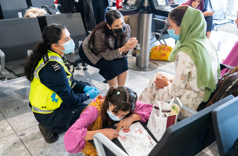  Britain's Home Secretary Priti Patel speaks to Malalai Hussiny a refugee from Afghanistan who arrived on a evacuation flight, at Heathrow Airport, in London, Britain August 26, 2021. (photo credit: DOMINIC LIPINSKI/REUTERS)
