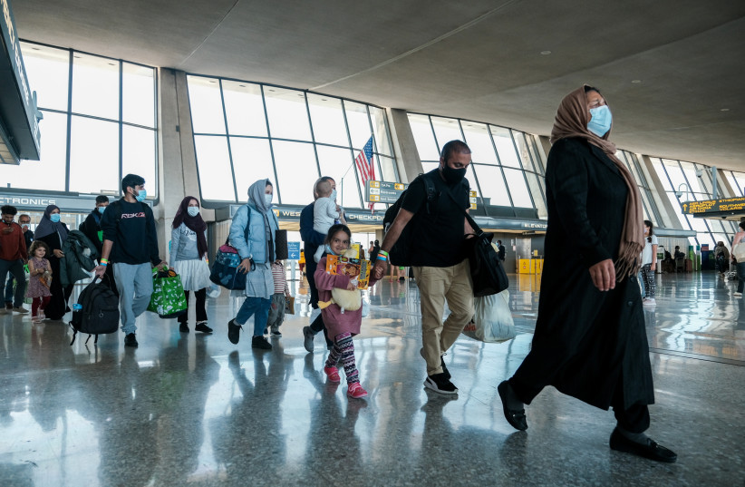  Afghan refugees walk to a bus taking them to a processing center upon arrival at Dulles International Airport in Dulles, Virginia, US. (photo credit: MICHAEL A. MCCOY/REUTERS)