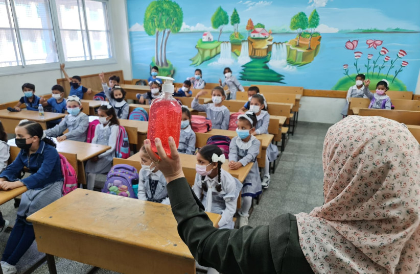  A teacher talks to her students about the importance of hand-washing with hand sanitizer on the first day of the new school year in the Gaza Strip, August 16, 2021. (credit: HASSAN ESLIEH/THE MEDIA LINE)