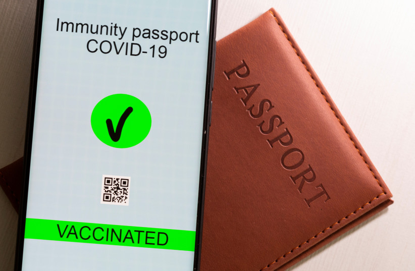  A smartphone with displayed "Immunity passport COVID-19" is placed on a passport in this illustration taken April 27, 2021 (photo credit: REUTERS)