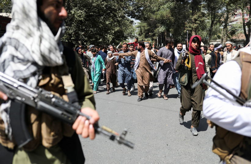  Taliban soldiers walk in front of protesters during the anti-Pakistan protest in Kabul, Afghanistan, September 7, 2021. (credit: WANA (WEST ASIA NEWS AGENCY) VIA REUTERS)
