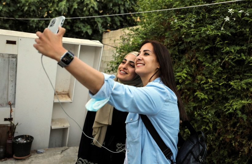     A woman takes a selfie with prominent Palestinian activist Muna al-Kurd in the courtyard of Muna's home in Sheikh Jarrah's East Jerusalem(Credit: Reuters/Ammar Awad)