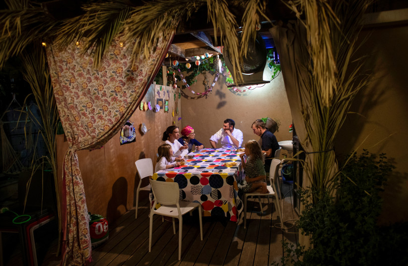  The Stanleigh family sit inside their sukka, or ritual booth, used during the Jewish holiday of Sukkot in their yard, in Jerusalem October 14, 2019. Picture taken October 14, 2019. (credit: RONEN ZVULUN/REUTERS)
