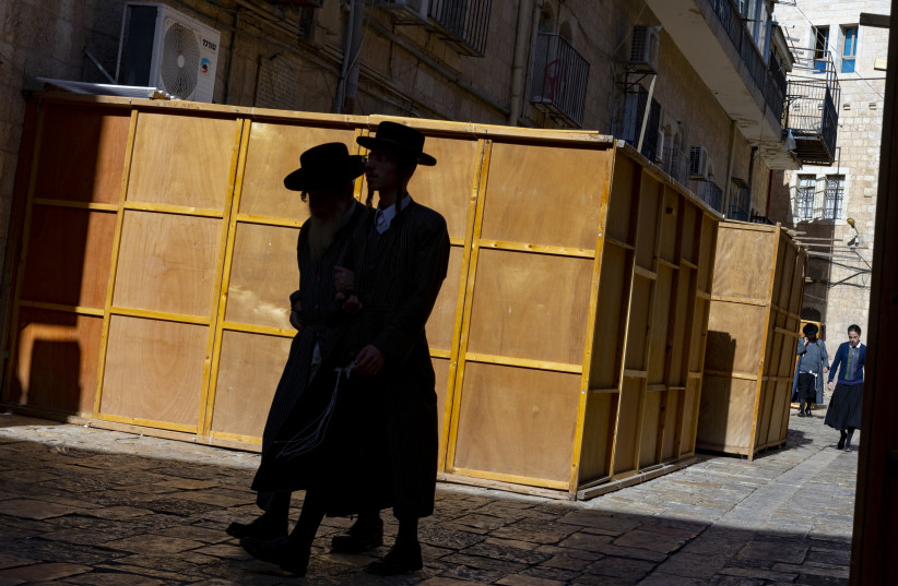  Ultra orthodox jews walk by a ''Sukkah'' (temporary dwelling), in the ultra orthodox jewish neighborhood of Mea Shearim in Jerusalem on September 09, 2021.  (credit: OLIVIER FITOUSSI/FLASH90)