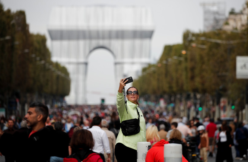  A woman takes a selfie near the Arc de Triomphe monument, fully wrapped as part of an art installation entitled "L'Arc de Triomphe, Wrapped" conceived by the late artists Christo and Jeanne-Claude, on the Champs Elysees avenue during a car-free sunday in Paris, France, September 19, 2021. (photo credit: REUTERS/BENOIT TESSIER)