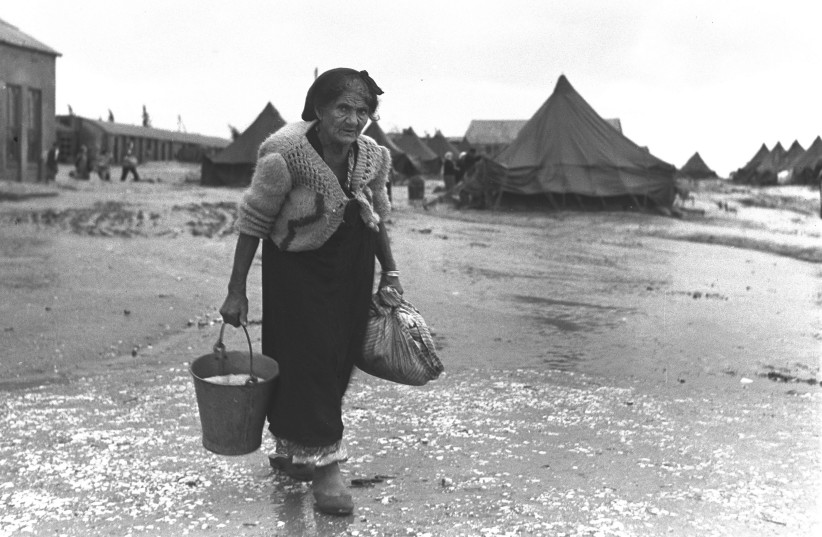 AN ELDERLY YEMENITE immigrant goes out in the muddy fields to fetch drinking water at the Beit Lid transit camp after the torrential rains in December 1949 (credit: TEDDY BRAUNER/GPO)