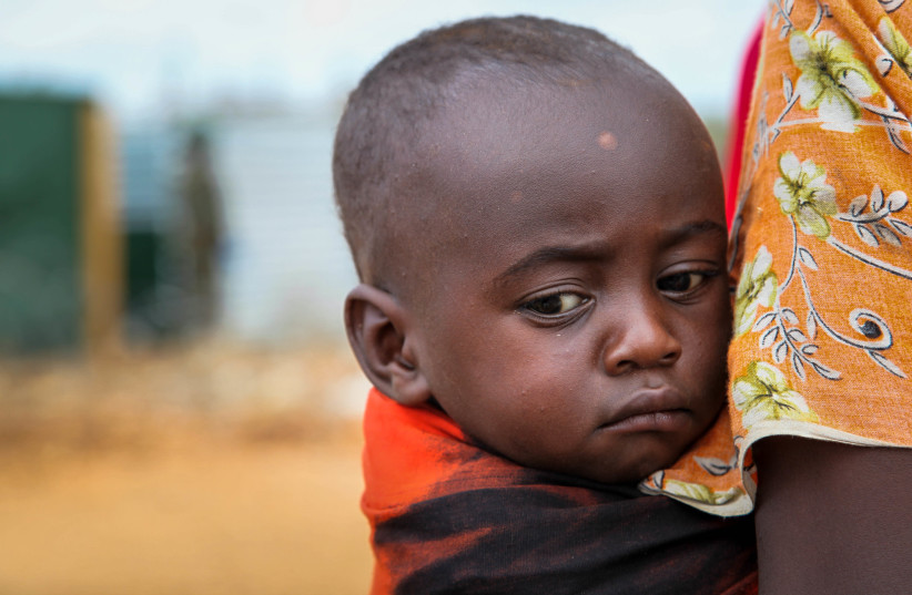  A woman holds a young child while they wait to enter a medical clinic. (photo credit: ABDI DAKAN via Flickr)