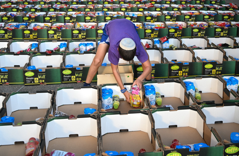  Israeli soldiers and volunteers pack boxes with food for families in need ahead of the Jewish holiday of Sukkot and the Jewish New Year, organized by the Horowitz family in memory of their son Eylon who died during his military service, in Avney Eitan, Golan Heights, September 2, 2021 (photo credit: MICHAEL GILADI/FLASH90)
