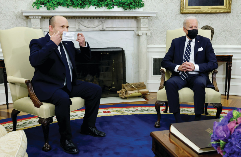  PRIME MINISTER Naftali Bennett holds a mask during a meeting with US President Joe Biden at the White House last month. (photo credit: REUTERS/JONATHAN ERNST)