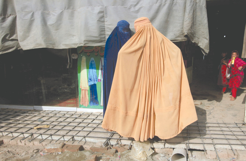 AFGHAN WOMEN, clad in burkas, stand outside a shop at a market in Peshawar, Pakistan. (photo credit: REUTERS/ FAYAZ AZIZ)