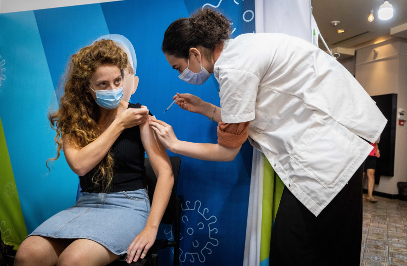  A woman receives a dose of the COVID-19 vaccine at a temporary Clalit health care center in Jerusalem, September 30, 2021.  (credit: YONATAN SINDEL/FLASH90)