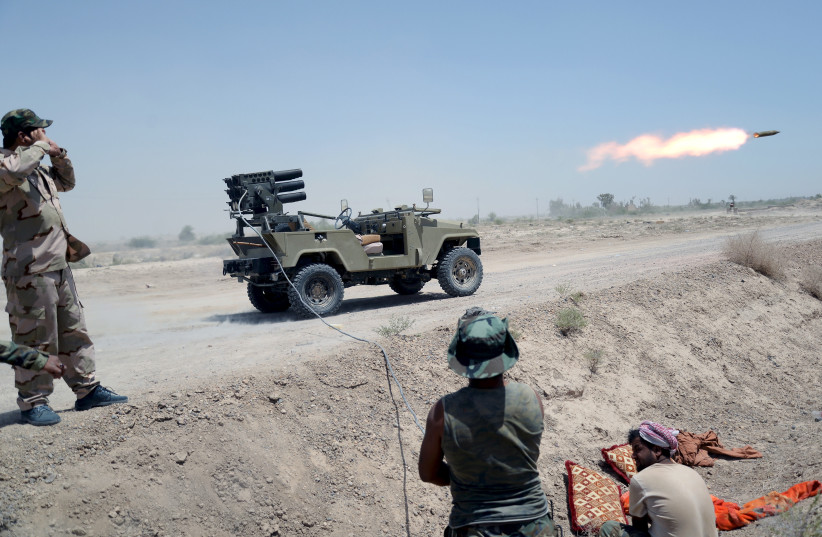  IRAQI SHI’ITE paramilitaries  launch a rocket towards Islamic  State operatives, north of  Fallujah, 2015. (photo credit: STRINGER/ REUTERS)