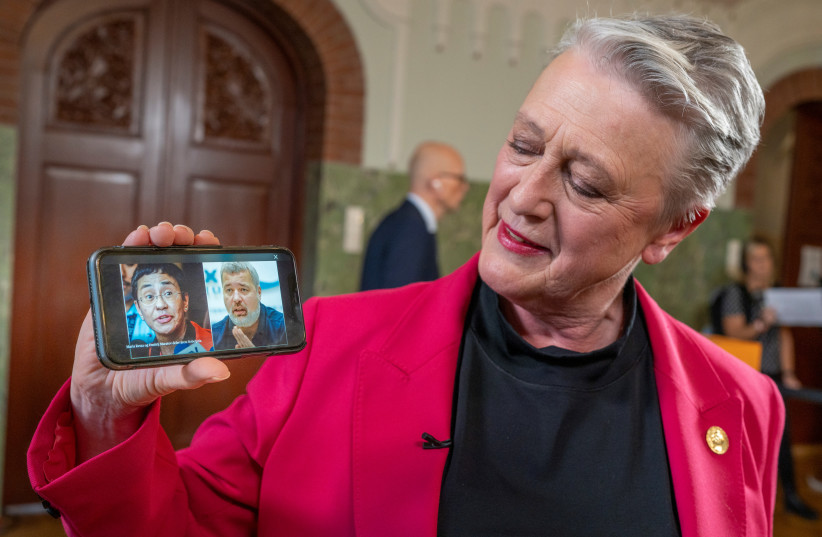  Chair of the Norwegian Nobel Peace Prize Committee Berit Reiss-Andersen shows on a mobile phone laureates of the 2021 Nobel Peace Prize, journalists Maria Ressa and Dmitry Muratov, in the Nobel Institute in Oslo, Norway (photo credit: NTB/Heiko Junge via REUTERS)