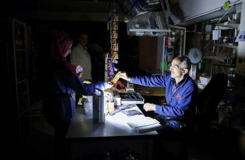  People shop in a grocery store under a portable electric light during a power cut near Bhamdoun, Lebanon, October 9, 2021 (photo credit: REUTERS/MOHAMED AZAKIR)