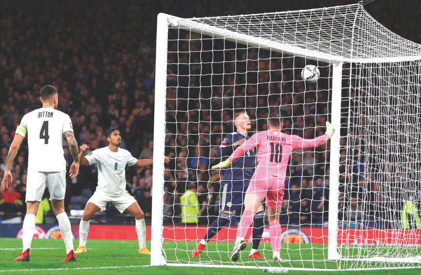 Scotland midfielder Scott McTominay scores the winning goal past Israel ’keeper Ofir Marciano late in stoppage time of the teams’ World Cup Group F qualifier on Saturday night at Hampden Park, where the hosts earned a 3-2 victory. Glasgow, Scotland, Britain, October 9, 2021. (photo credit: ACTION IMAGES / LEE SMITH VIA REUTERS)