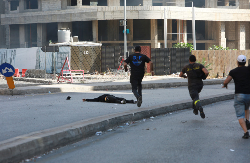  Men run to rescue a person shot while preparing to fire a rocket-propelled grenade, during a gunfire in Beirut, Lebanon October 14, 2021. (credit: AZIZ TAHER/REUTERS)