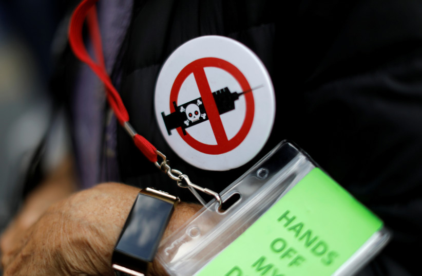  A man wears an anti-vaccine button as people and teachers protest against New York City mandated vaccines (photo credit: REUTERS/MIKE SEGAR)