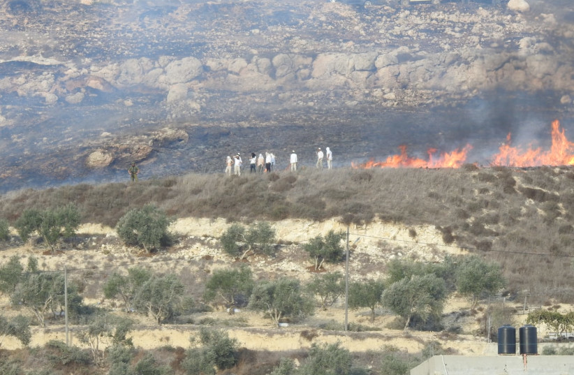  Israelis can be seen standing near a fire they started near the Palestinian village of Burin, October 16, 2021 (credit: YESH DIN)
