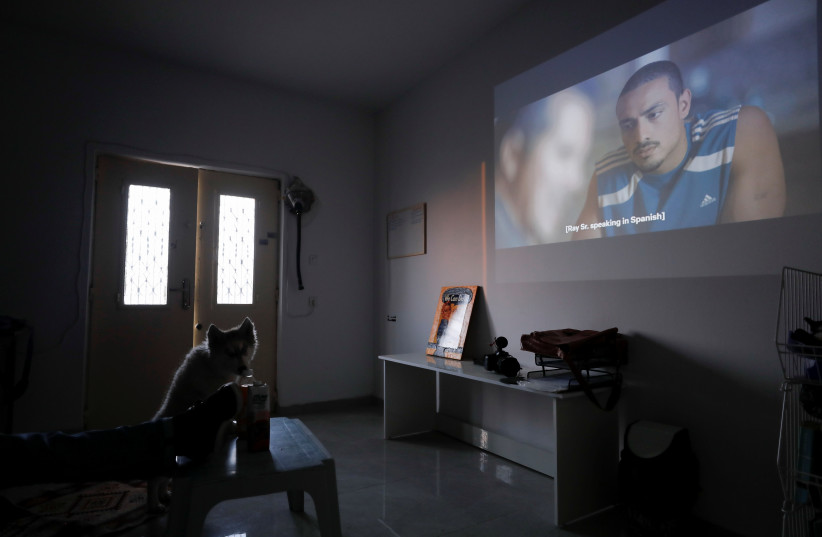 Palestinian Abdallah Maraka watches a series on Netflix in his house in Hebron, October 14, 2021 (credit: REUTERS/MUSSA QAWASMA)