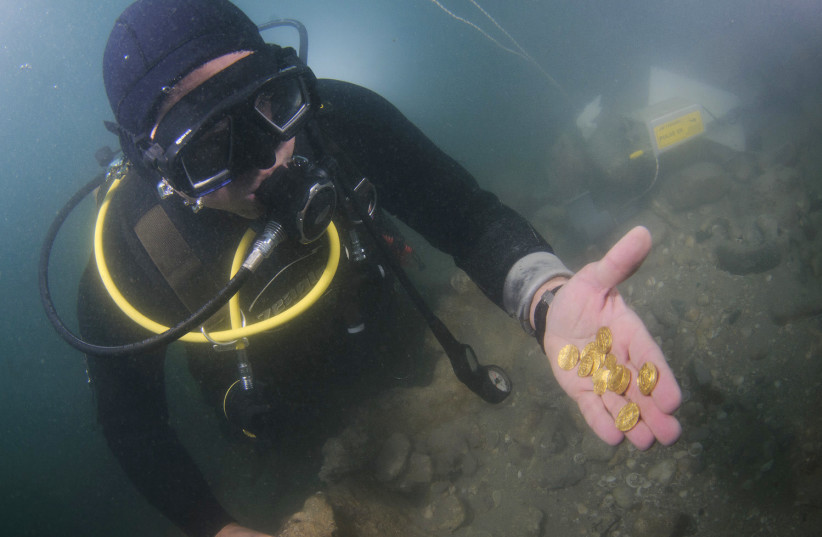  Diver holding gold coins (credit: Hagai Nativ - Israel Antiquities Authority)