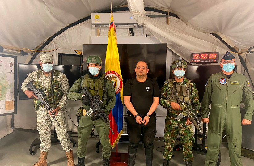  Dairo Antonio Usuga David, alias "Otoniel", top leader of the Gulf clan, poses for a photo escorted by Colombian military soldiers after being captured, in Necocli, Colombia October 23, 2021 (photo credit: COLOMBIA'S MILITARY FORCES/VIA REUTERS)
