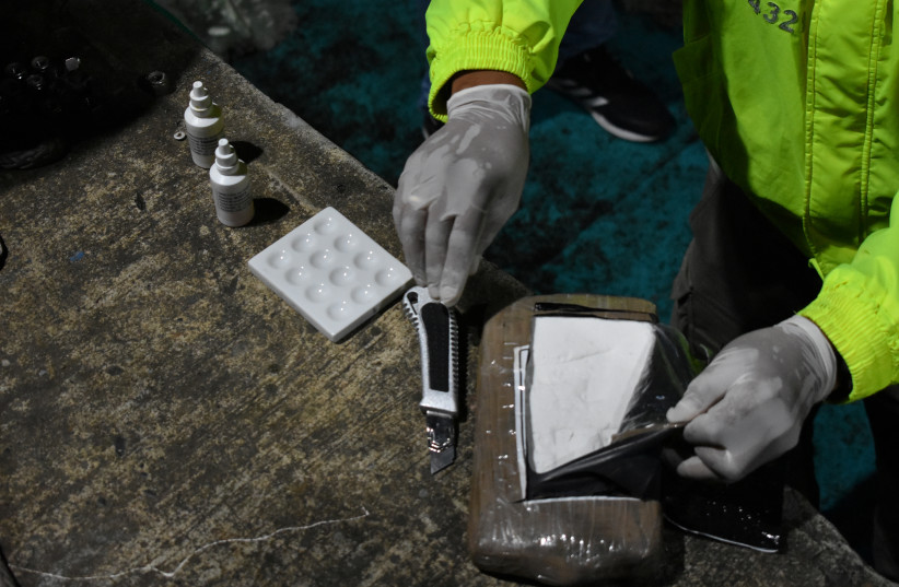  A police officer opens a cocaine hydrochloride package during the seizure of a semi-submersible sea vessel loaded with more than a ton of cocaine hydrochloride in Tumaco, Colombia August 23, 2020 (credit: VIA REUTERS)