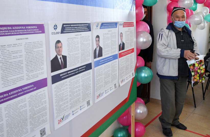 A voter walks near a board displaying information about candidates, including Uzbek incumbent President Shavkat Mirziyoyev, at a polling station during a presidential election in Tashkent, Uzbekistan, October 24, 2021. (credit: STRINGER/ REUTERS)