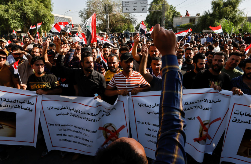 Supporters of Iraqi Shiite armed groups hold signs and flags during a protest against the election results, near the Green Zone in Baghdad, Iraq October 19, 2021. (photo credit: THAIER AL-SUDANI/REUTERS)