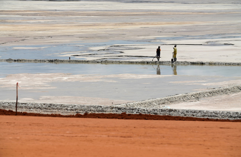  Workers are pictured on a plain of sludge on a tailings dam at the Kibali gold mine in Haut-Uele province, Democratic Republic of Congo October 8, 2021.  (photo credit: REUTERS/Hereward Holland)