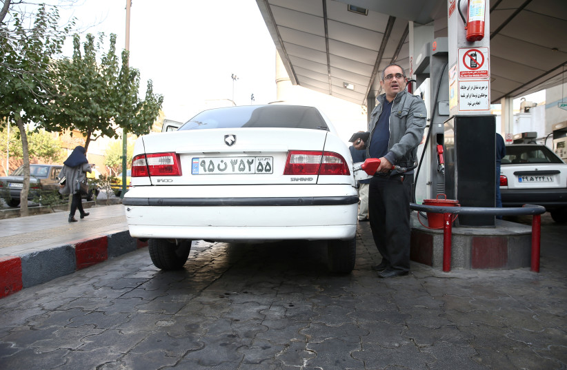 A man fills up his car's tank at a petrol station, after fuel price increased in Tehran (photo credit: REUTERS)