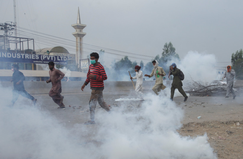  Supporters of the banned Islamist political party Tehrik-e-Labaik Pakistan (TLP) run amid the smoke of tear gas during a protest demanding the release of their leader and the expulsion of the French ambassador over cartoons depicting the Prophet Mohammed, in Lahore, Pakistan, October 23, 2021. (credit: REUTERS/MOHSIN RAZA/FILE PHOTO)