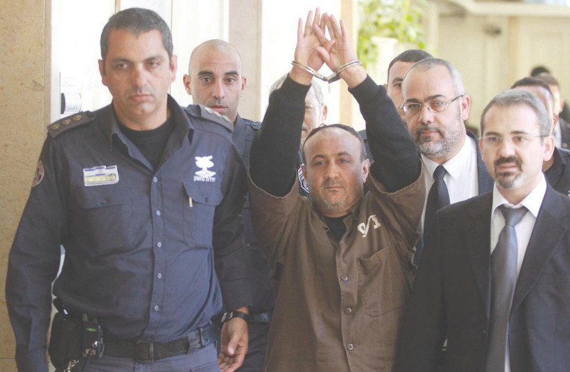 MARWAN BARGHOUTI is escorted in handcuffs by police into Jerusalem Magistrates Court in 2012. (photo credit: FLASH90)