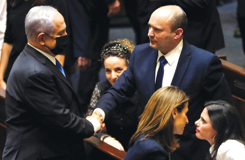  Opposition leader Benjamin Netanyahu shakes hands with Prime Minister Naftali  Bennett following the vote on the new coalition in the Knesset on June 13.  (credit: RONEN ZVULUN/REUTERS)
