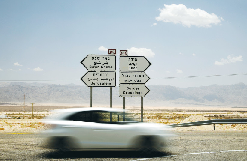 A road sign near Eilat points in different directions. Is the car coming from Beersheba or Be’er Sheva? (photo credit: AMIR COHEN/REUTERS)