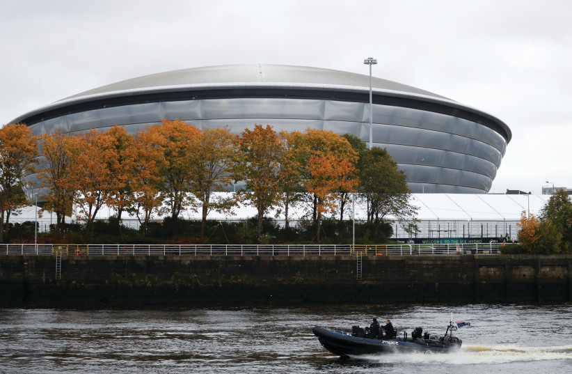 POLICE OFFICERS patrol on a boat at the River Clyde, opposite the Scottish Event Campus, where the COP26 will take place, in Glasgow, next week. (photo credit: RUSSELL CHEYNE/REUTERS)