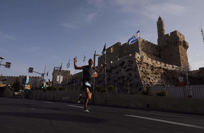 A RUNNER is seen by the Old City walls during Jerusalem's 10th Annual Marathon, October 29, 2021 (credit: MARC ISRAEL SELLEM/THE JERUSALEM POST)