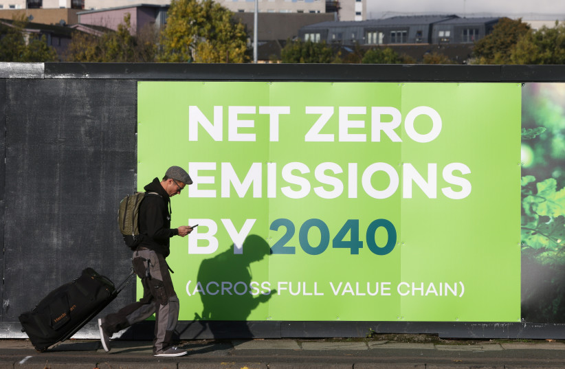  A man walks past a advertising in relation with the UN Climate Change Conference (COP 26) where world leaders discuss how to tackle climate change on a global scale, near the conference area in Glasgow Scotland, Britain October 30, 2021.  (credit: REUTERS/YVES HERMAN)