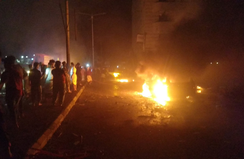  People look at cars on fire at the site of an explosion outside Aden international airport in Aden, Yemen. (photo credit: OSAMA AL-MAHRAMI/REUTERS)