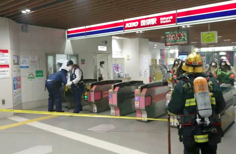 Firefighters and officers work at a Tokyo train station following a knife and arson attack in Tokyo, Japan, October 31, 2021, in this still image obtained from a social media video. (photo credit: TWITTER/@SIZ33/VIA REUTERS)