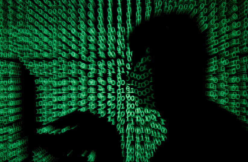  A man holds a laptop computer as cyber code is projected on him in this illustration picture taken on May 13, 2017.  (credit: REUTERS/KACPER PEMPEL/ILLUSTRATION/FILE PHOTO)