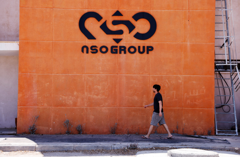  A man walks past the logo of Israeli cyber firm NSO Group at one of its branches in the Arava Desert, southern Israel July 22, 2021 (credit: REUTERS/AMIR COHEN)